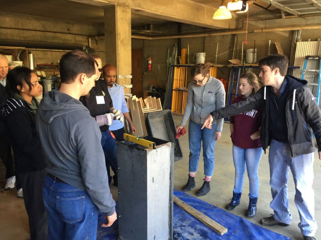 Our CAWST volunteer shows students the best way to prep the metal mold for concrete pouring.