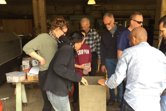 Students inspect the finished concrete biosand water filter after taking it out of the mold.